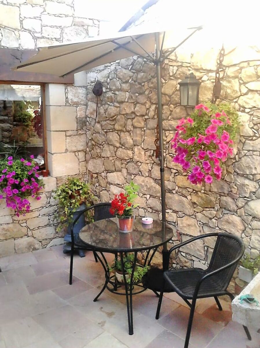 Patio con mesa, sillas y flores bajo la sombrilla
